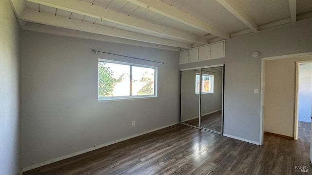 unfurnished bedroom featuring dark wood-style flooring, a closet, beam ceiling, and baseboards