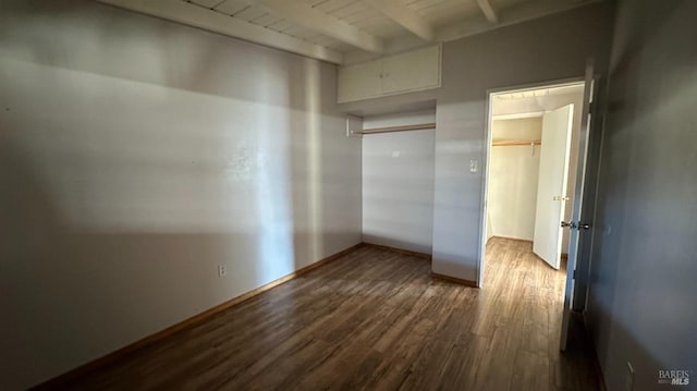 empty room featuring dark wood-type flooring, beam ceiling, and baseboards