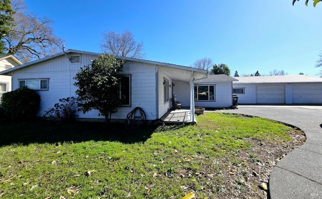 single story home with a front yard and a detached garage