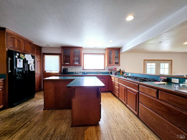 kitchen featuring stainless steel gas stovetop, wood finished floors, black fridge with ice dispenser, and a center island