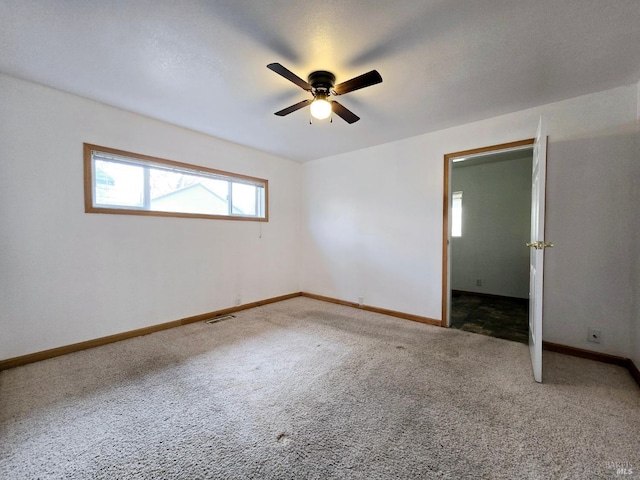 empty room with carpet, visible vents, and baseboards