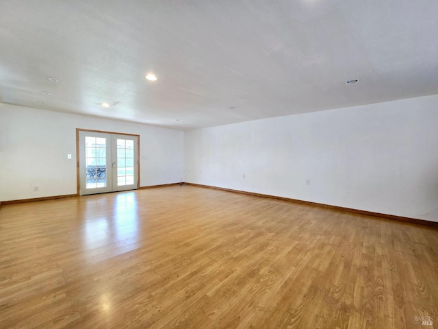 empty room with french doors, baseboards, and light wood finished floors