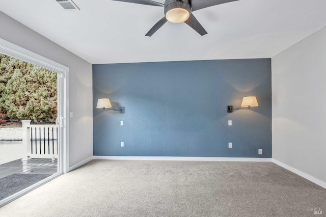 carpeted spare room featuring baseboards, visible vents, and ceiling fan