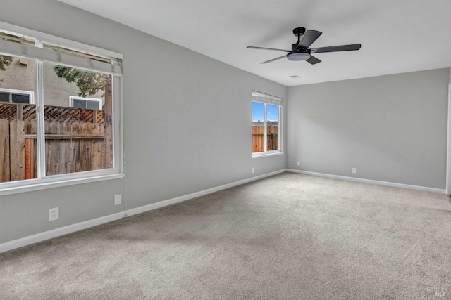 carpeted spare room featuring a ceiling fan and baseboards