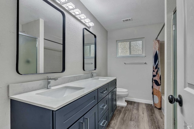 full bath featuring curtained shower, visible vents, a sink, and wood finished floors