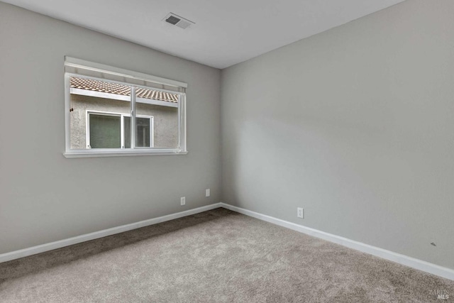 empty room featuring carpet, visible vents, and baseboards