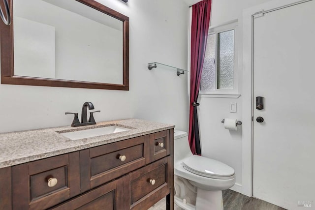 bathroom with toilet, wood finished floors, and vanity