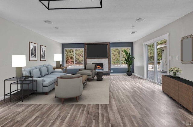 living room with visible vents, a fireplace, baseboards, and wood finished floors