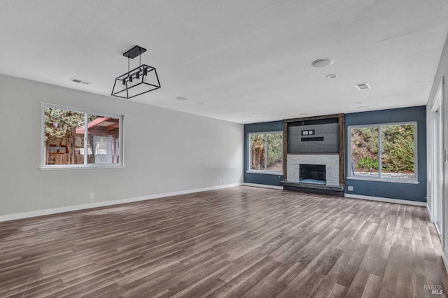 unfurnished living room with baseboards, a fireplace, visible vents, and wood finished floors