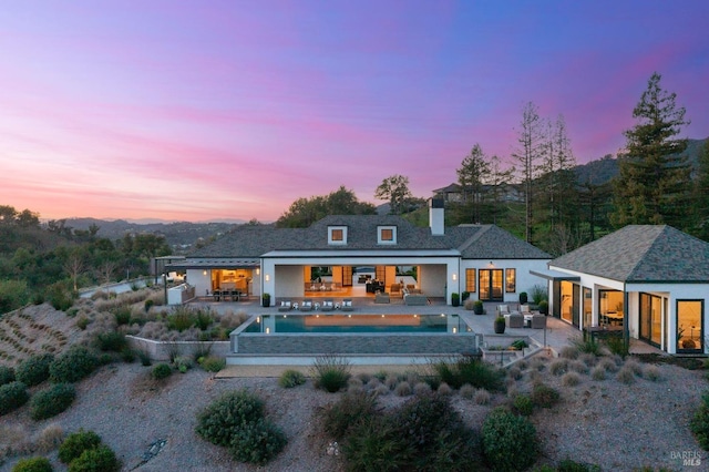 back of house with a patio, an outdoor structure, an outdoor living space, a chimney, and an exterior structure