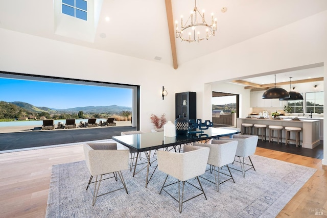 dining space with light wood-type flooring, an inviting chandelier, a mountain view, and high vaulted ceiling