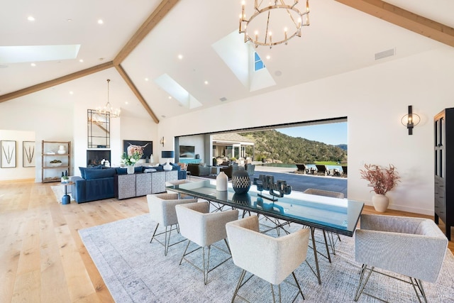 dining area featuring beamed ceiling, a skylight, light wood-style flooring, and a notable chandelier