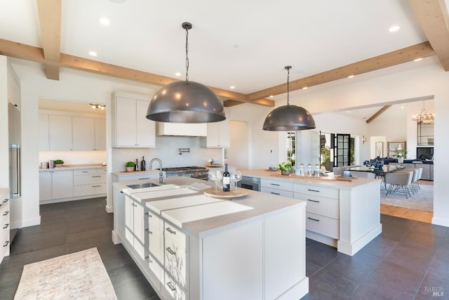 kitchen featuring recessed lighting, light countertops, backsplash, white cabinets, and an island with sink