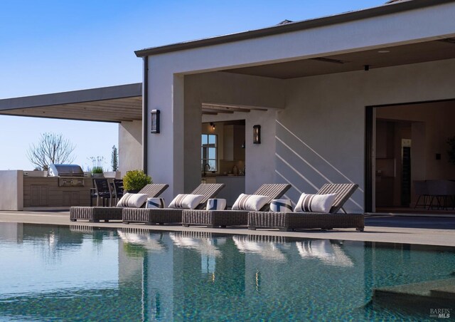 pool featuring a patio area, an outdoor kitchen, and grilling area