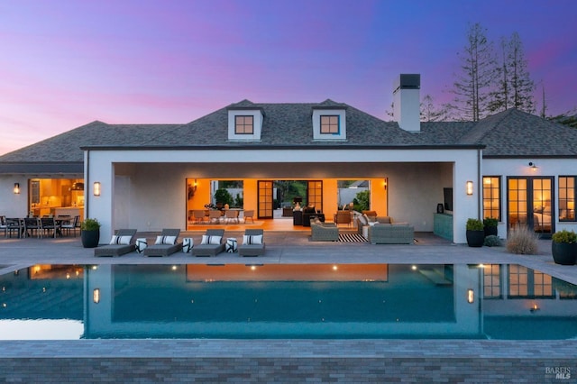 back of property at dusk featuring an outdoor hangout area, a patio, outdoor dining area, and a chimney