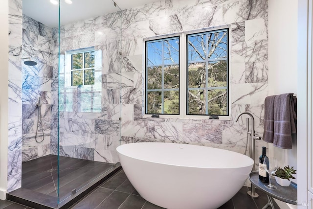 bathroom with a marble finish shower and a freestanding bath