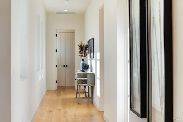 corridor with light wood-style floors, baseboards, and visible vents