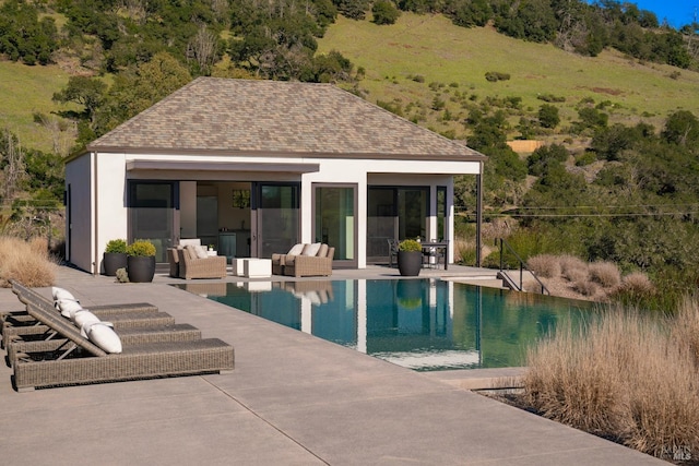 pool featuring a storage structure, a patio area, outdoor lounge area, and an outbuilding