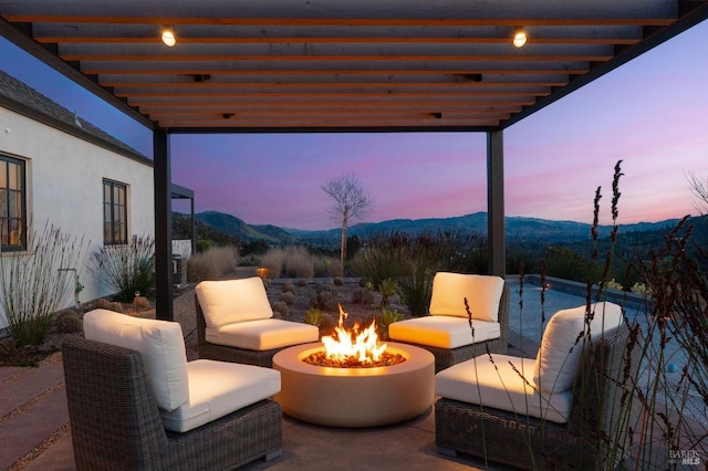 patio terrace at dusk featuring an outdoor living space with a fire pit and a mountain view