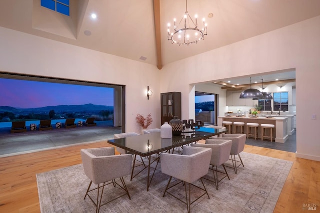 dining area featuring high vaulted ceiling, light wood-type flooring, and a notable chandelier