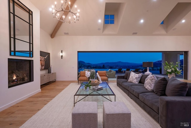 living room with wood finished floors, visible vents, a towering ceiling, baseboards, and a lit fireplace