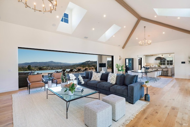 living room featuring a skylight, light wood-style floors, high vaulted ceiling, a mountain view, and a notable chandelier