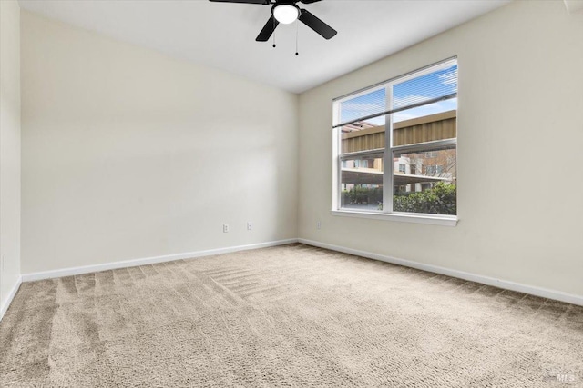 carpeted spare room with ceiling fan and baseboards