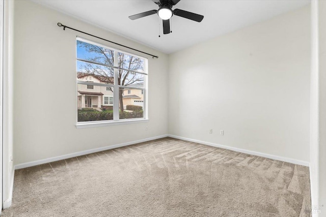 carpeted spare room featuring ceiling fan and baseboards