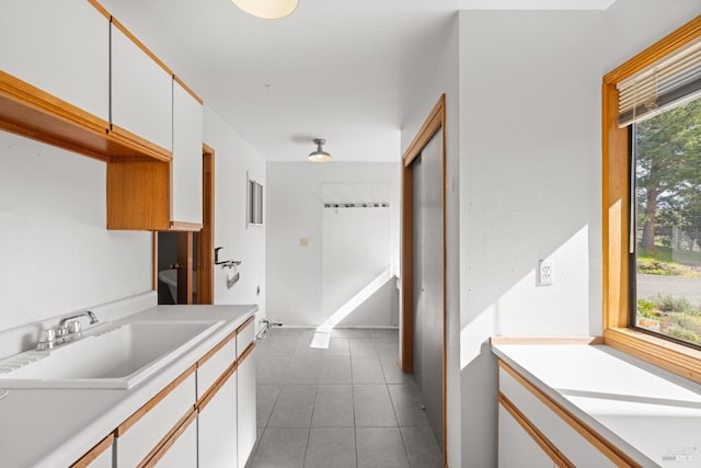 kitchen with light countertops, white cabinets, a sink, and tile patterned floors