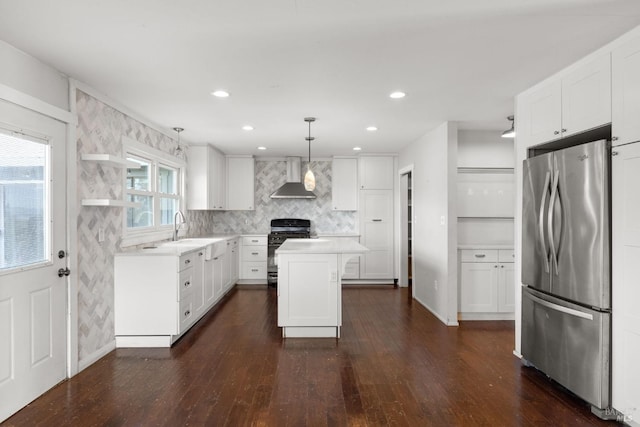 kitchen featuring range with gas stovetop, open shelves, freestanding refrigerator, a sink, and wall chimney range hood