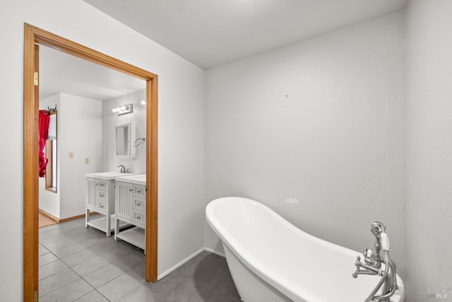 bathroom featuring baseboards, a soaking tub, vanity, and tile patterned floors