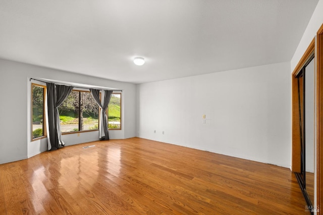 unfurnished room with light wood-type flooring and visible vents