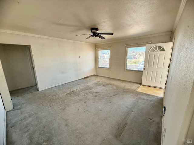 spare room with baseboards, a textured ceiling, a ceiling fan, and crown molding