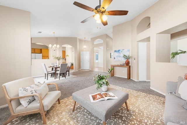 living room featuring baseboards, ceiling fan with notable chandelier, arched walkways, and light carpet