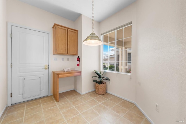 unfurnished dining area with light tile patterned flooring and baseboards