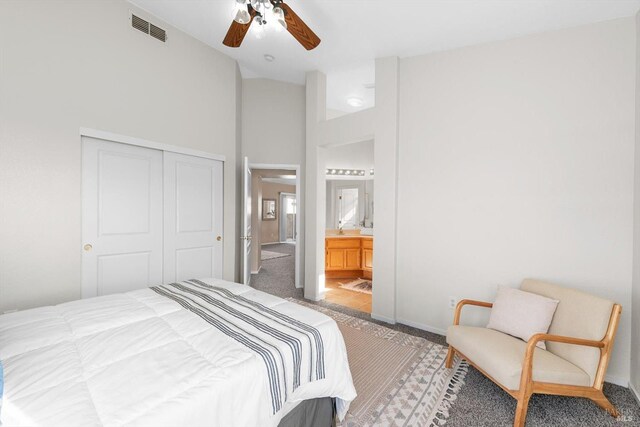 carpeted bedroom with visible vents, ensuite bath, lofted ceiling, ceiling fan, and a closet