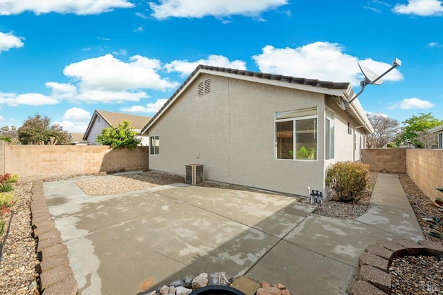 back of house with a patio area, central AC unit, a fenced backyard, and stucco siding