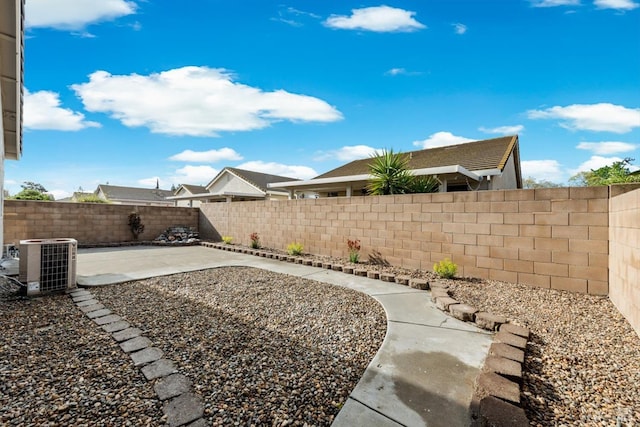 view of yard featuring a fenced backyard, central AC unit, and a patio