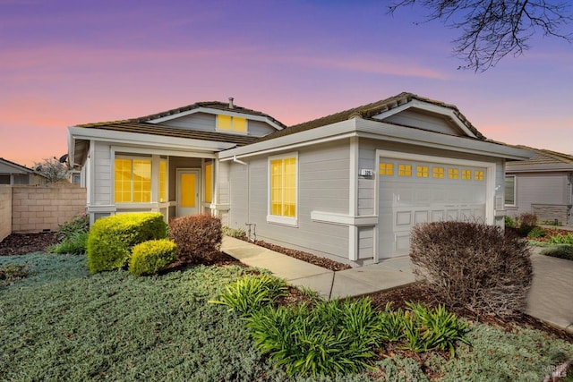 view of front of property with a tiled roof, fence, and a garage