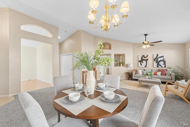 dining space with ceiling fan with notable chandelier, baseboards, and vaulted ceiling