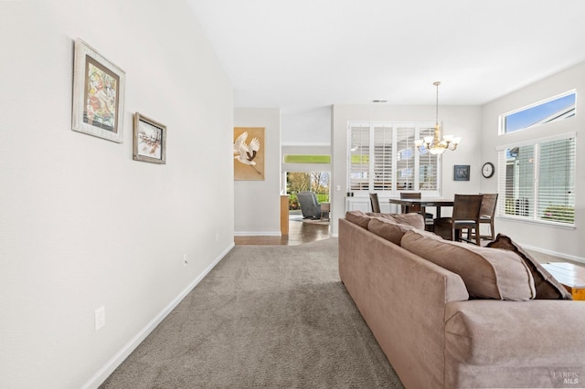 carpeted living area with baseboards and a notable chandelier