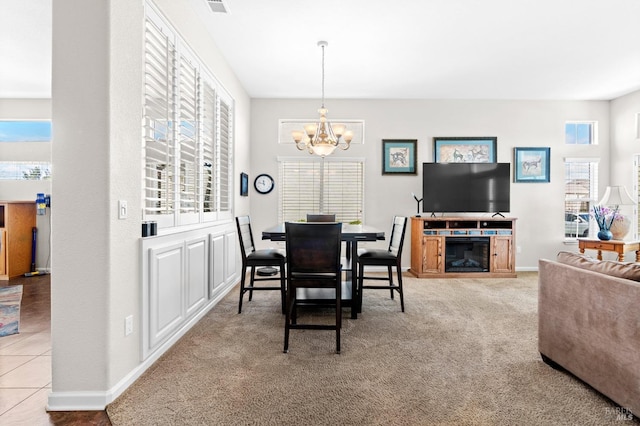 dining space featuring baseboards, a fireplace, carpet flooring, and a notable chandelier