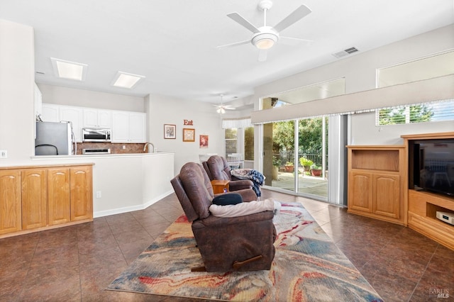 living room with ceiling fan, dark tile patterned flooring, and visible vents