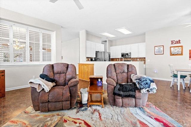 tiled living area with ceiling fan with notable chandelier and baseboards