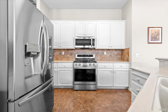 kitchen featuring stainless steel appliances, light countertops, white cabinetry, and decorative backsplash