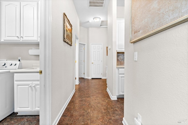 hallway with washer / dryer, attic access, baseboards, visible vents, and stone finish floor