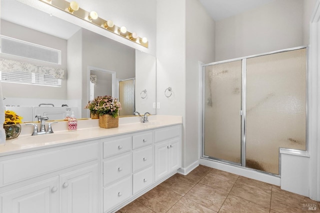 full bathroom with double vanity, a stall shower, tile patterned flooring, and a sink