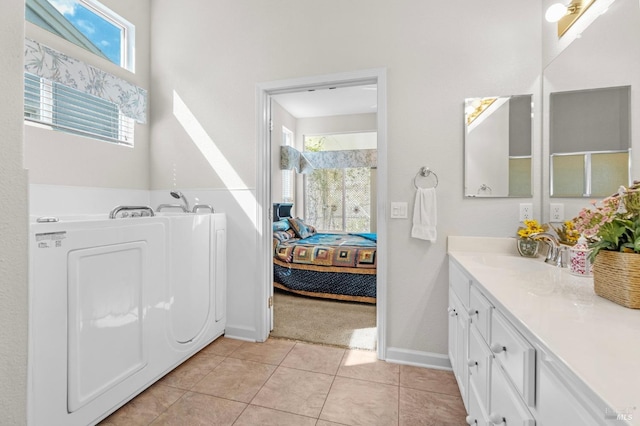 interior space with light tile patterned flooring, a sink, washer / dryer, and baseboards