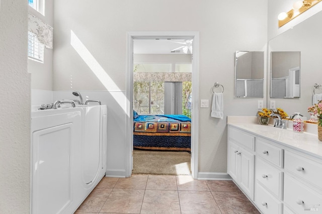 bathroom featuring tile patterned flooring, vanity, baseboards, ensuite bath, and washer / dryer