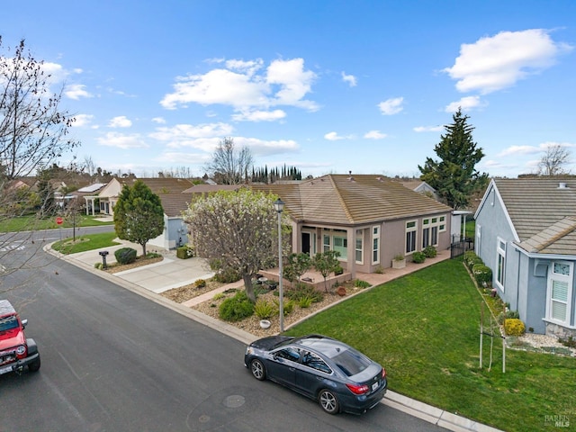 view of front facade featuring a tile roof, a residential view, and a front lawn